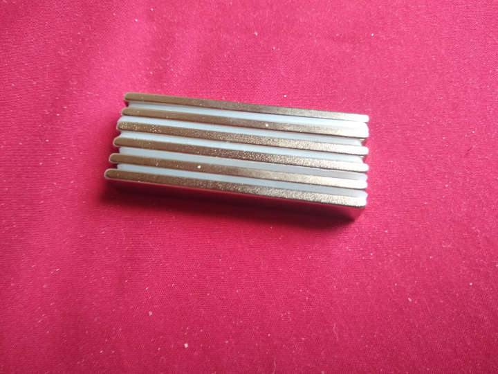 A stack of metal bars (magnets) with plastic dividers stuck together.