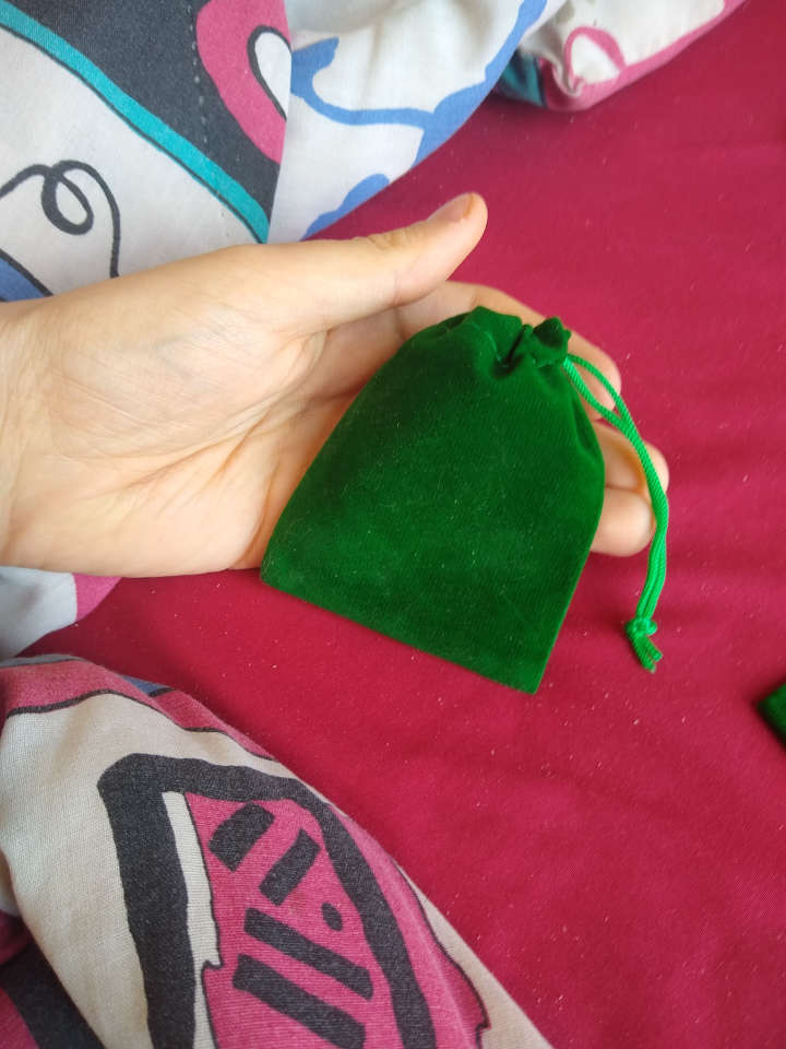 A small green bag with pull strings pulled closed.